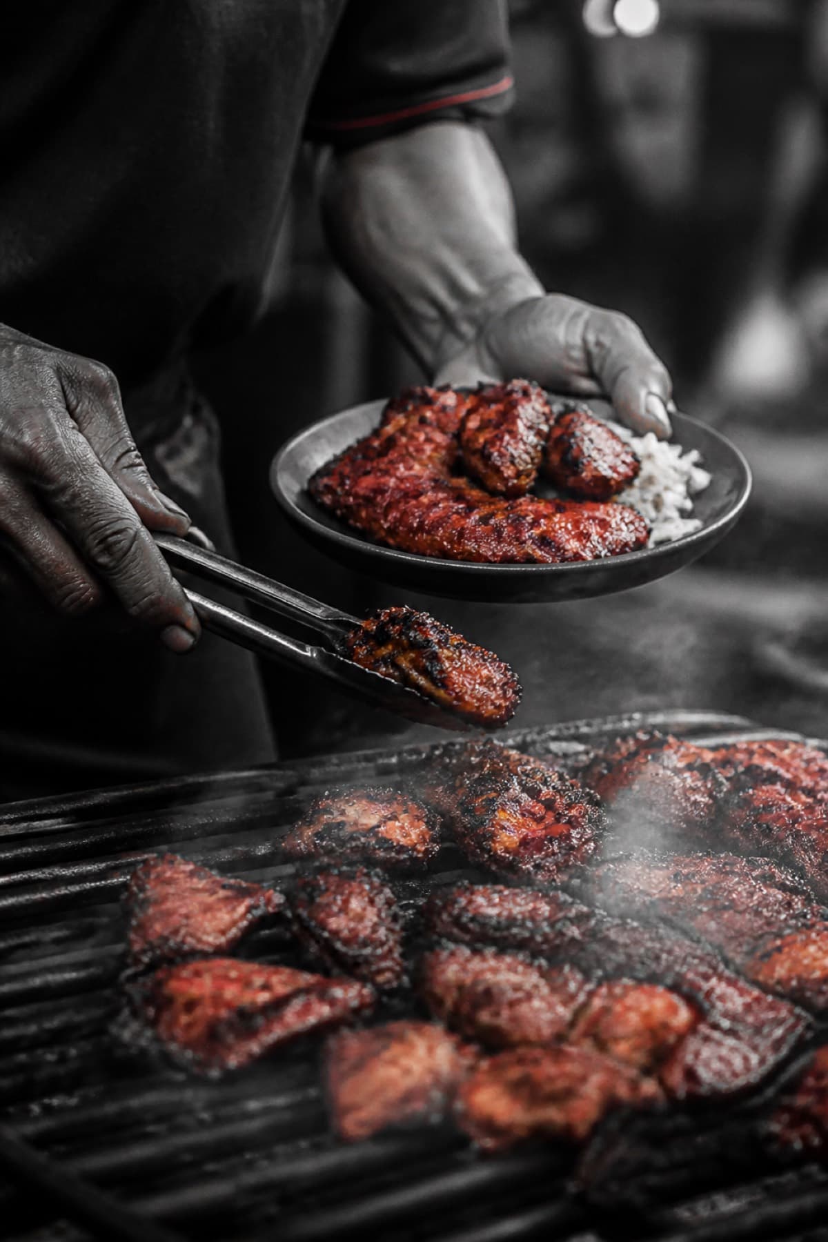 Hands plating grilled street food over smoke