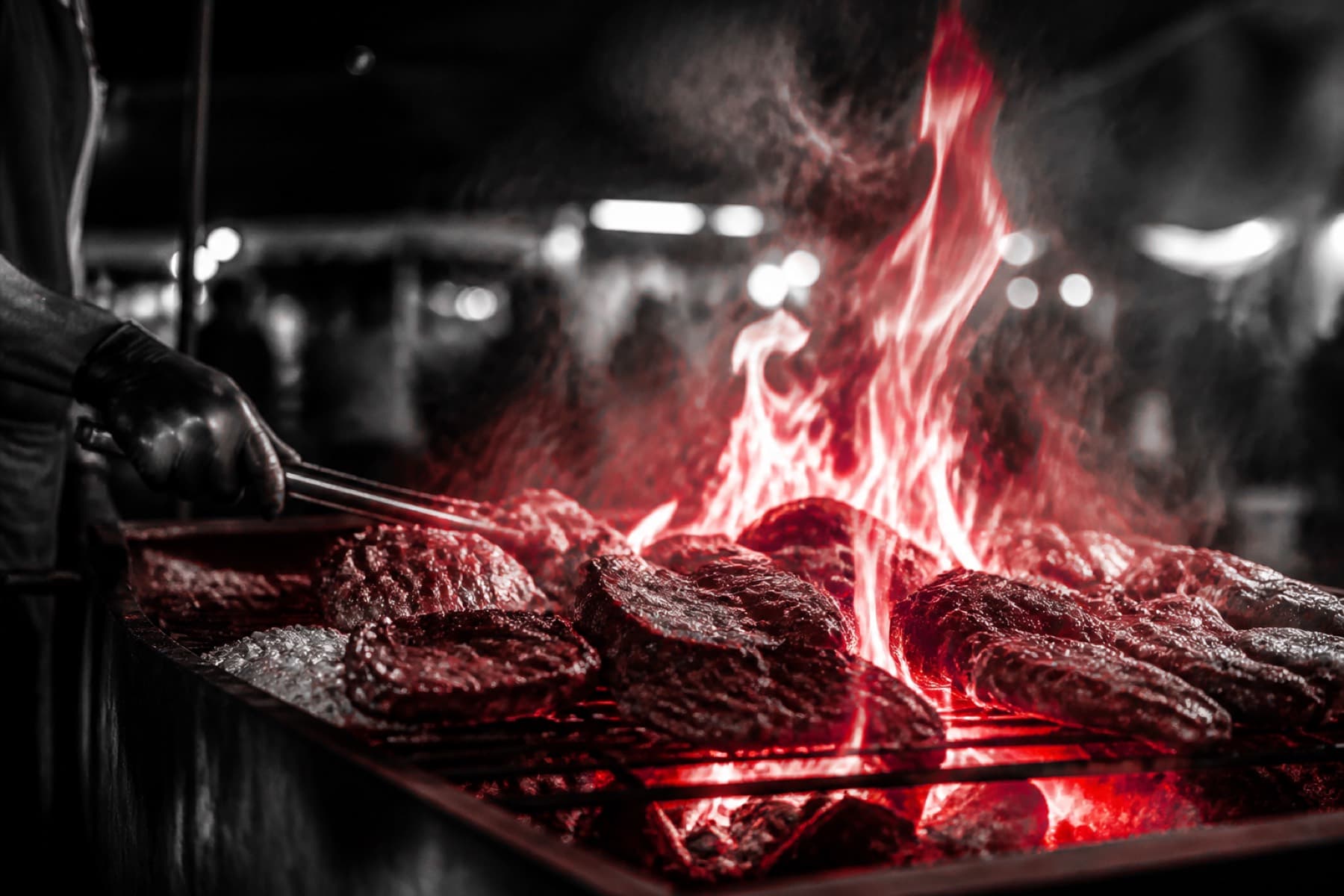 Flames rising from a BBQ grill at night