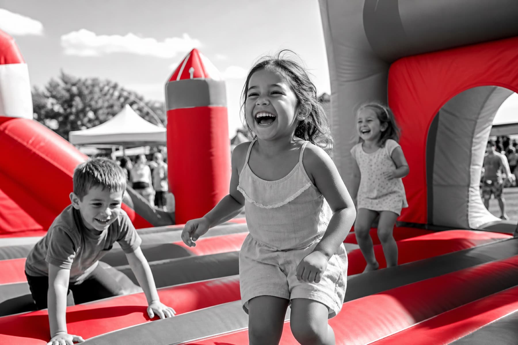 Children laughing on inflatable bounce structures at an outdoor family festival