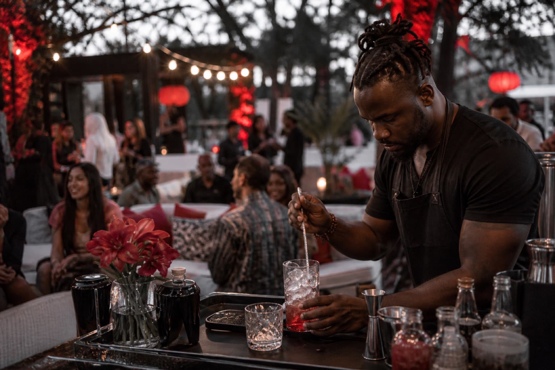 Outdoor festival lounge with string lights and a bartender preparing a cocktail